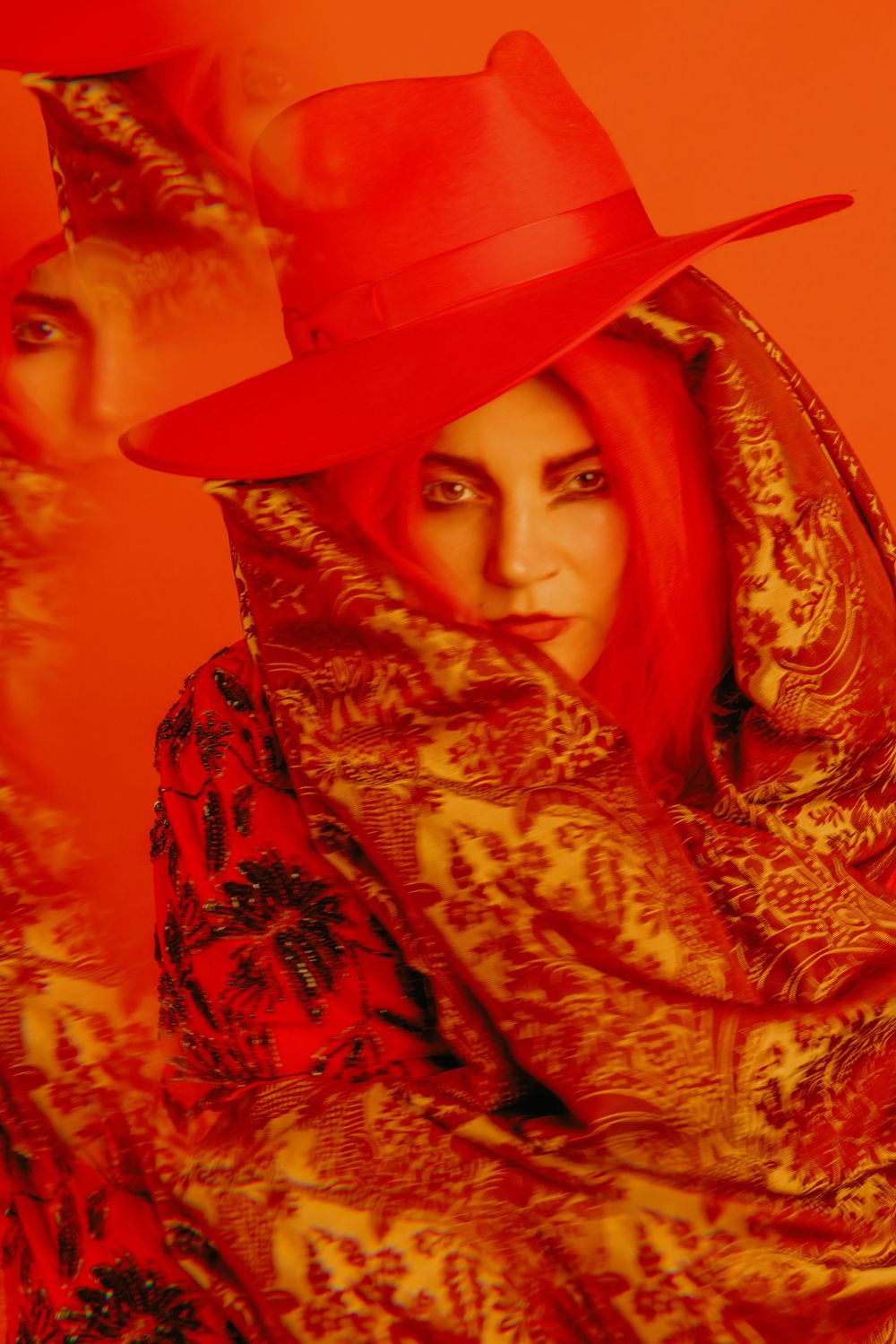 Artistic portrait series with red overlay featuring ornate patterned clothing and hat.
