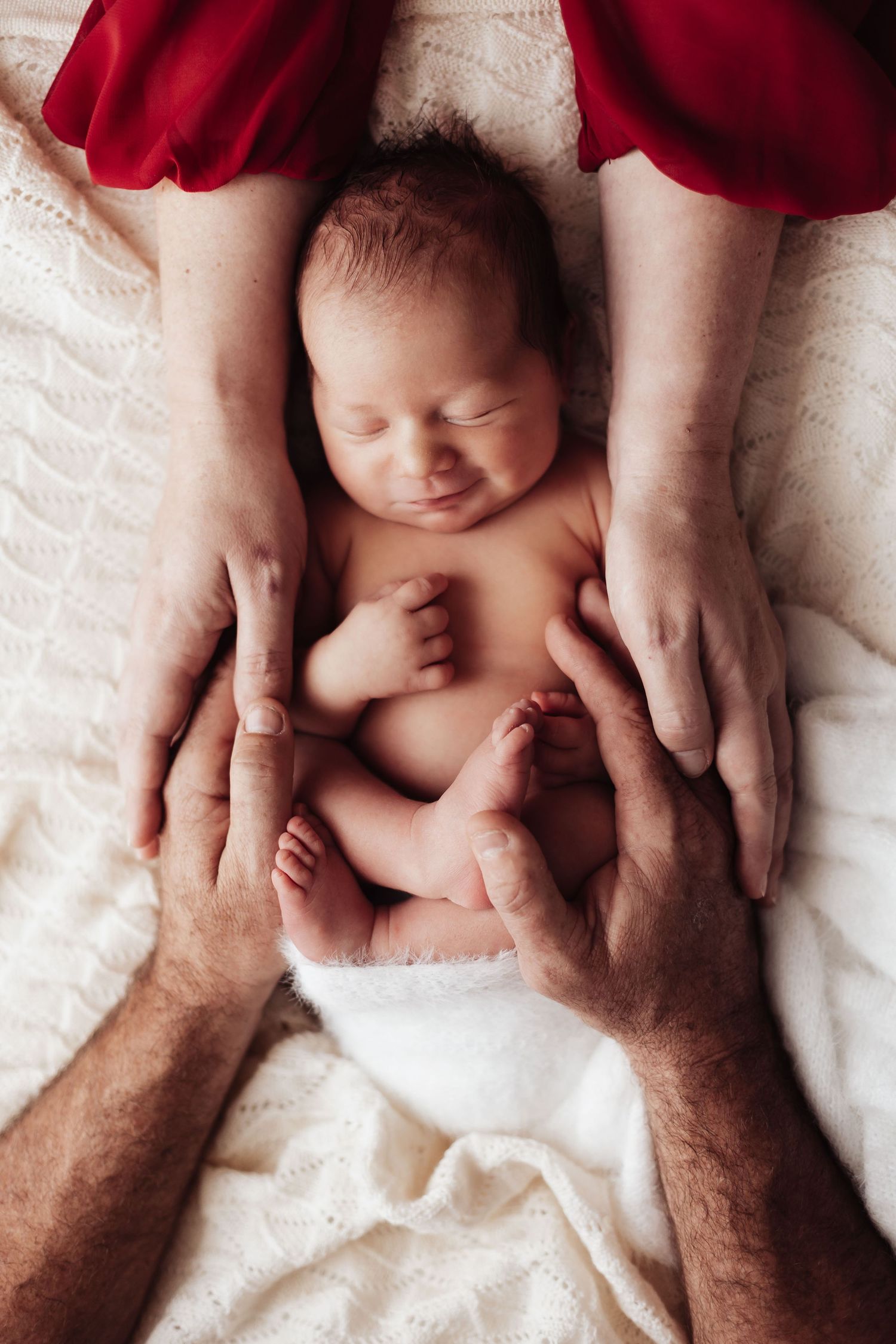 Sleeping newborn in brown knit outfit cuddling with teddy bear.