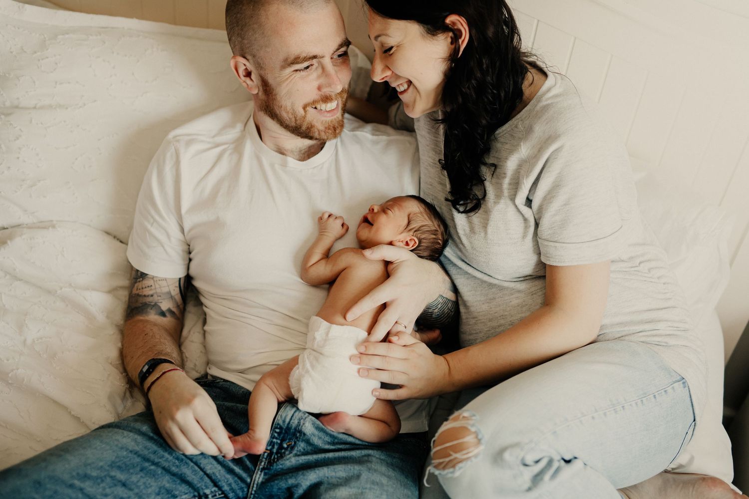 A father cradling his newborn baby and holding its hand
