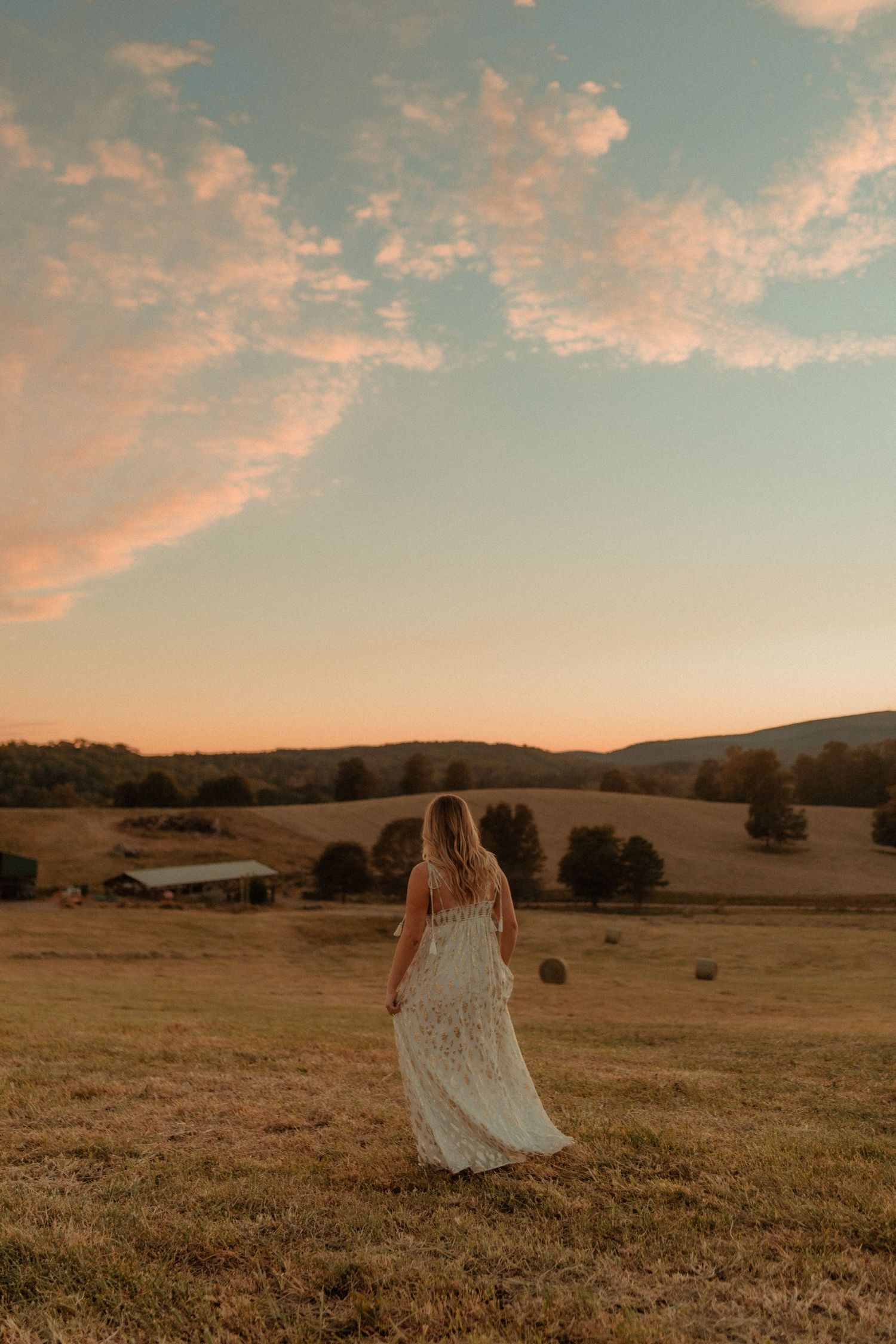 A dreamy sunset scene with flowing white dress in a golden countryside meadow.