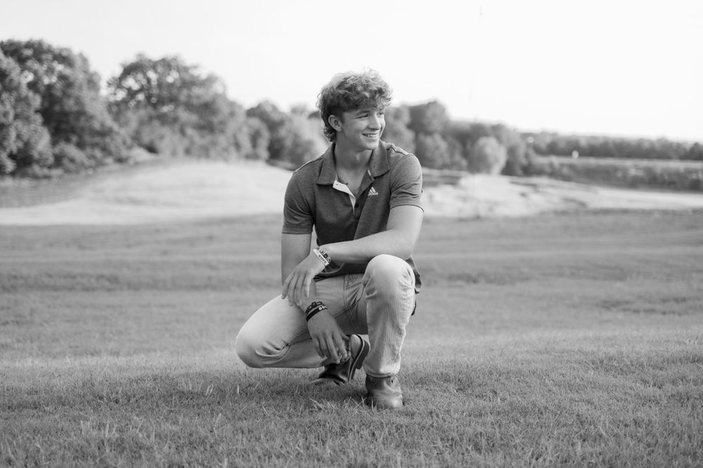 Black and white senior photo of young man in field