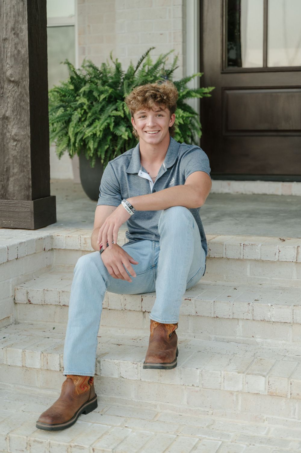Senior photo of young man sitting on front porch
