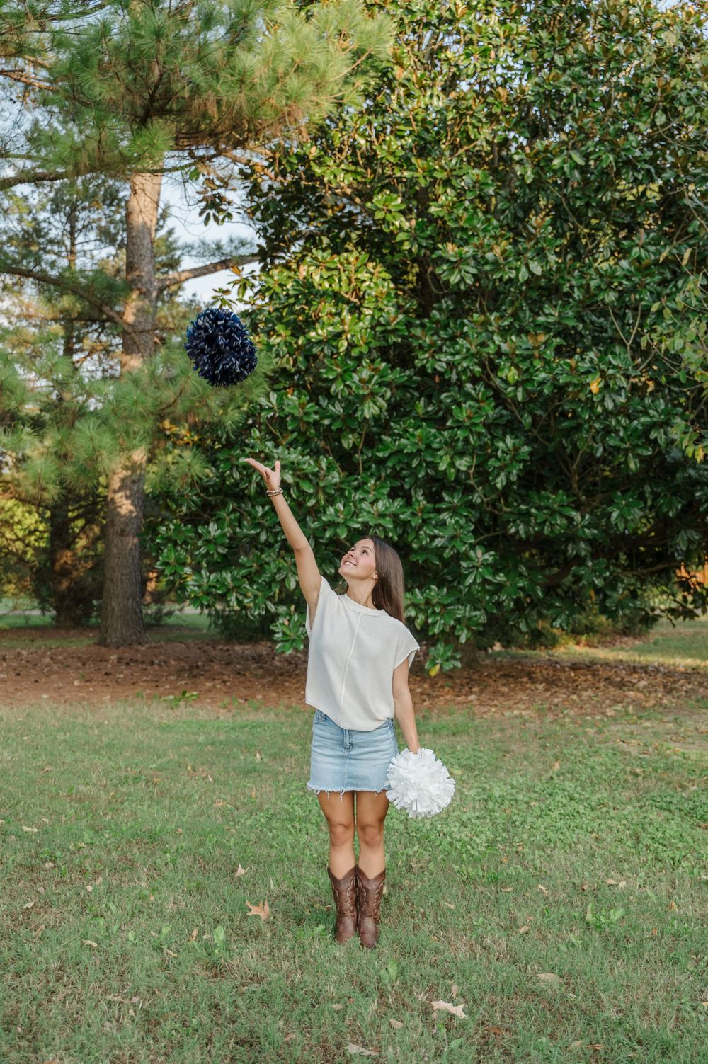 Senior portrait for cheer leader tossing pom poms