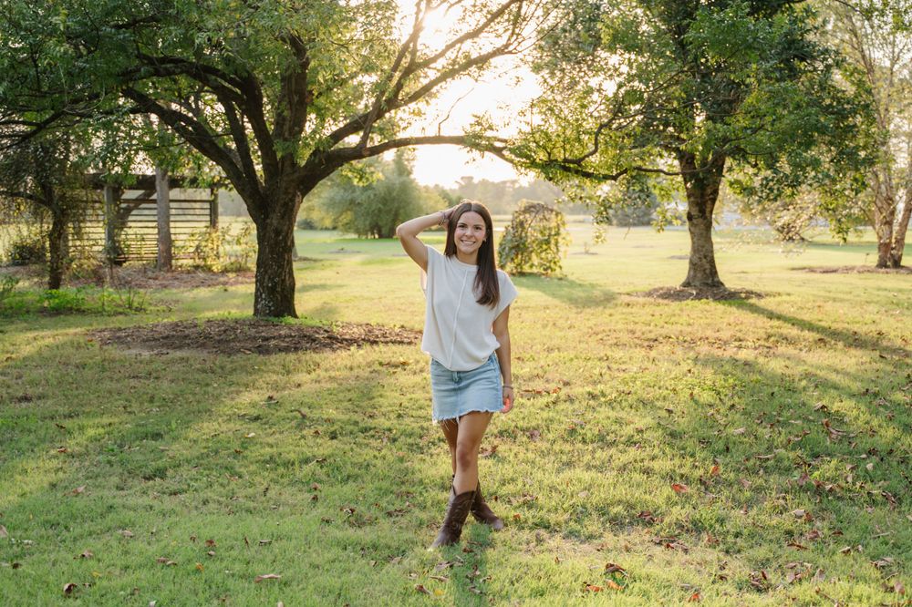 Bright and colorful portrait of girl walking through trees with sun beams behind her