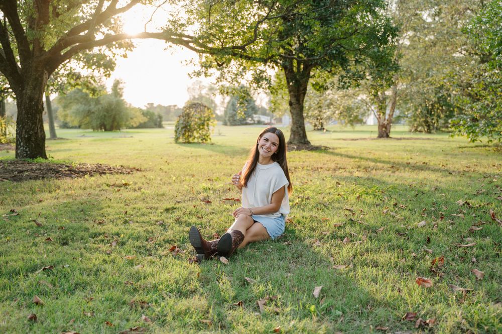 Girl sitting in field with sunbeams behind her