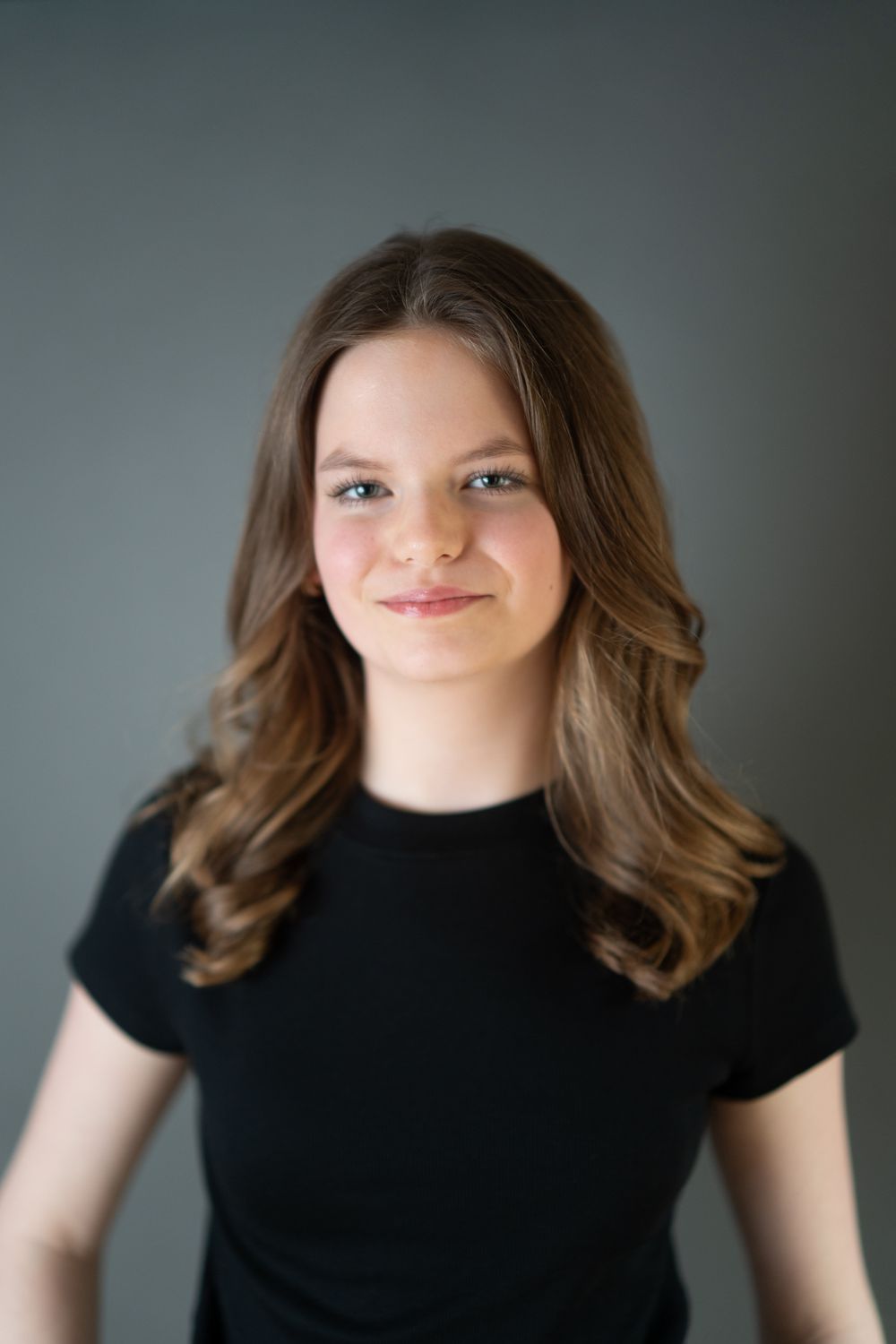 Young girls headshot wearing a black shirt on a dark grey backdrop