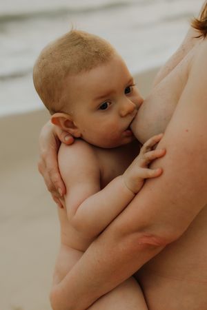 Intimate moment captured of baby breastfeeding while being cradled in mother's arms.