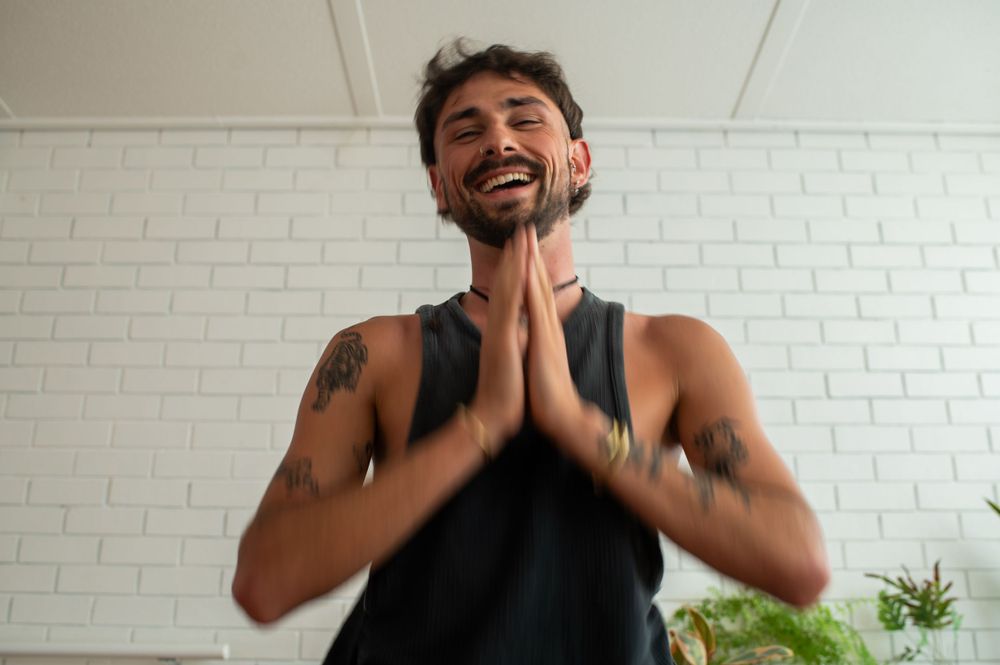 Man smiling with hands in prayer position