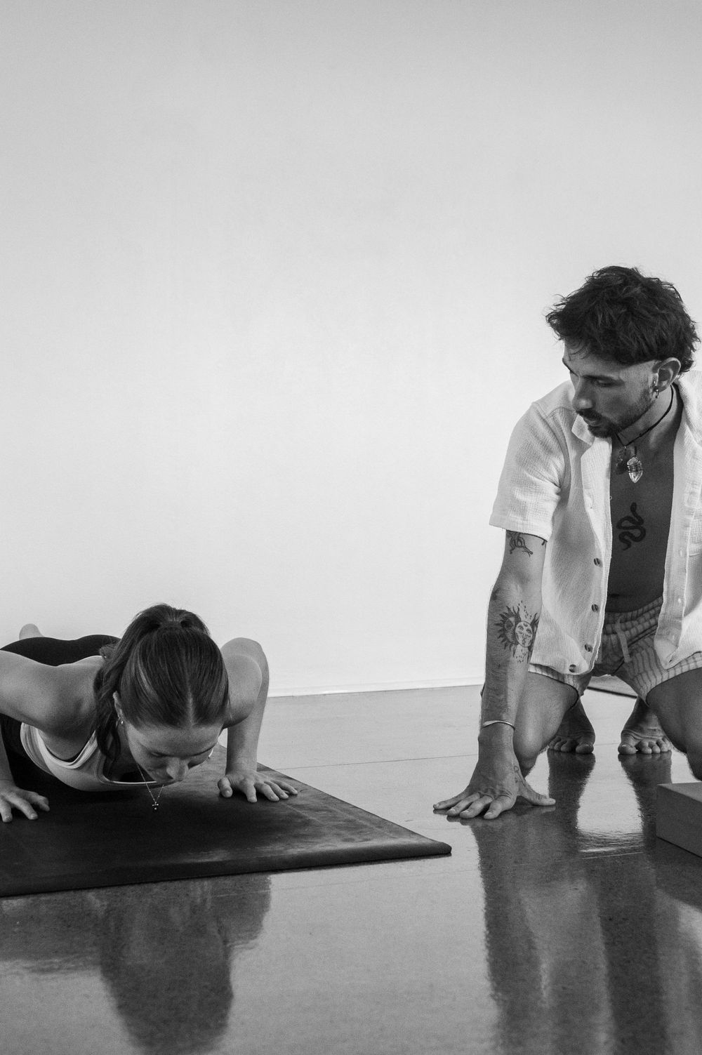 Woman doing yoga pose with teacher next to her