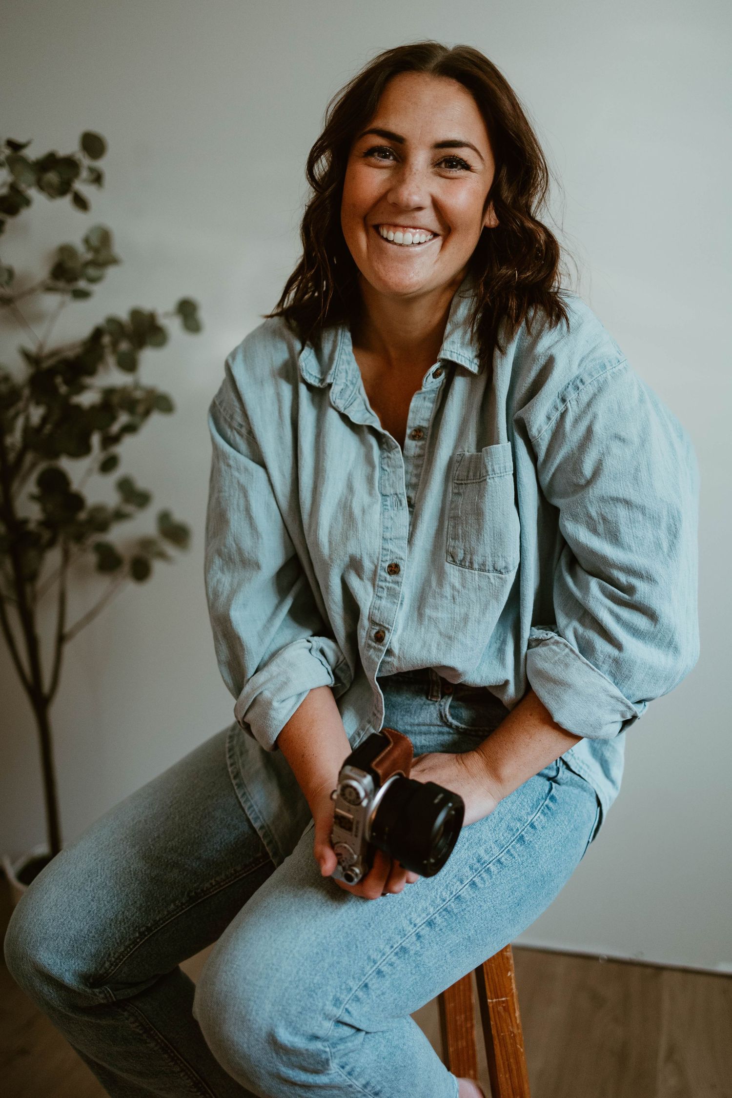 Candid portraits of someone in denim sitting on wooden chair with camera.