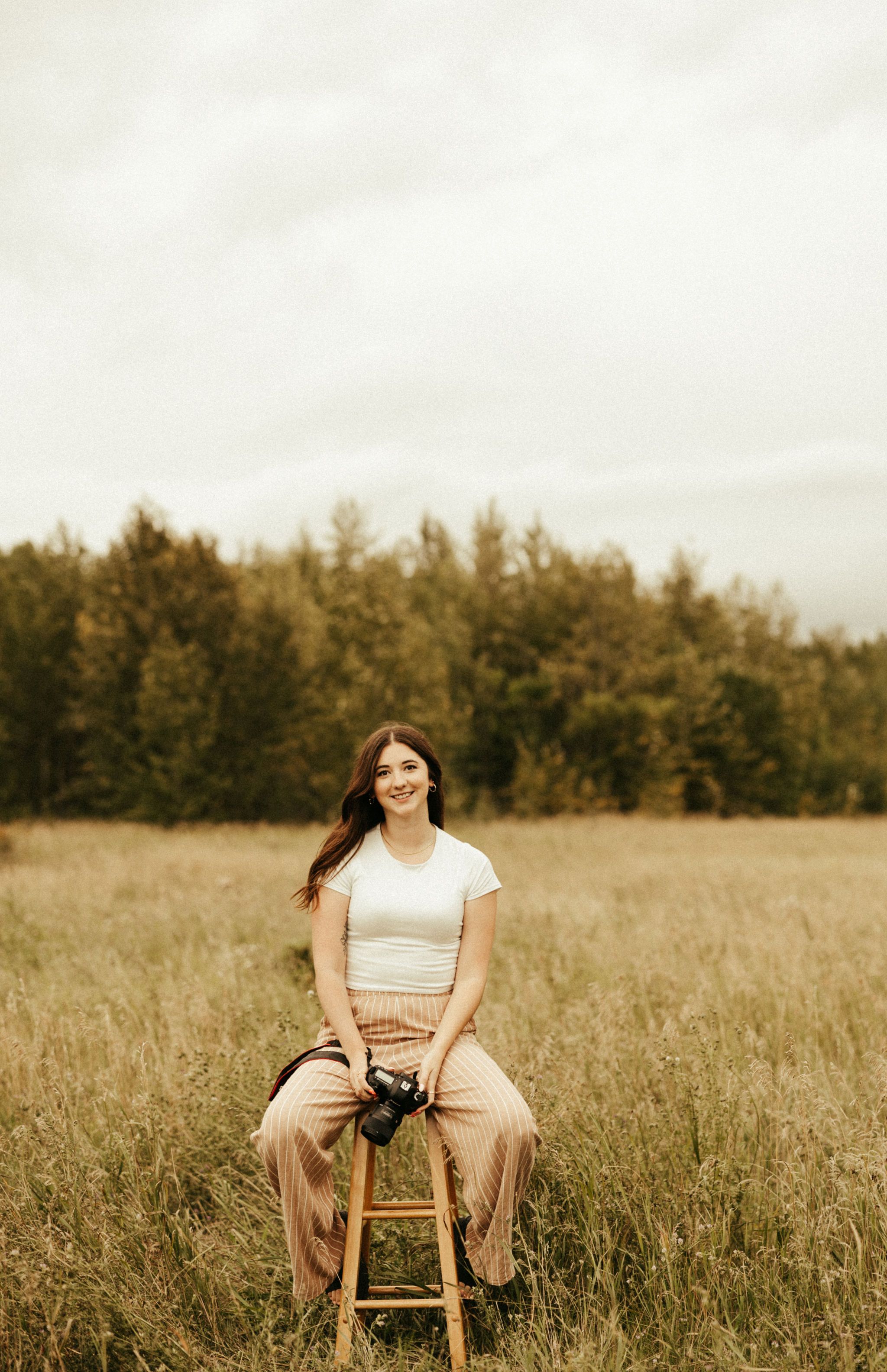 Brunette girl sitting on a stool outside looking at the camera