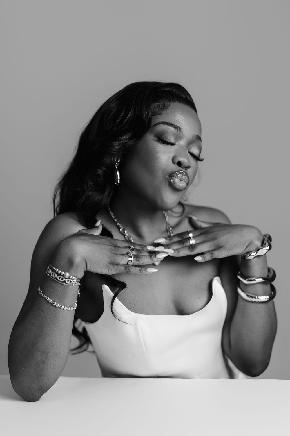 Artistic black and white photo series shows expressive poses with jewelry and a white garment against simple backdrop.