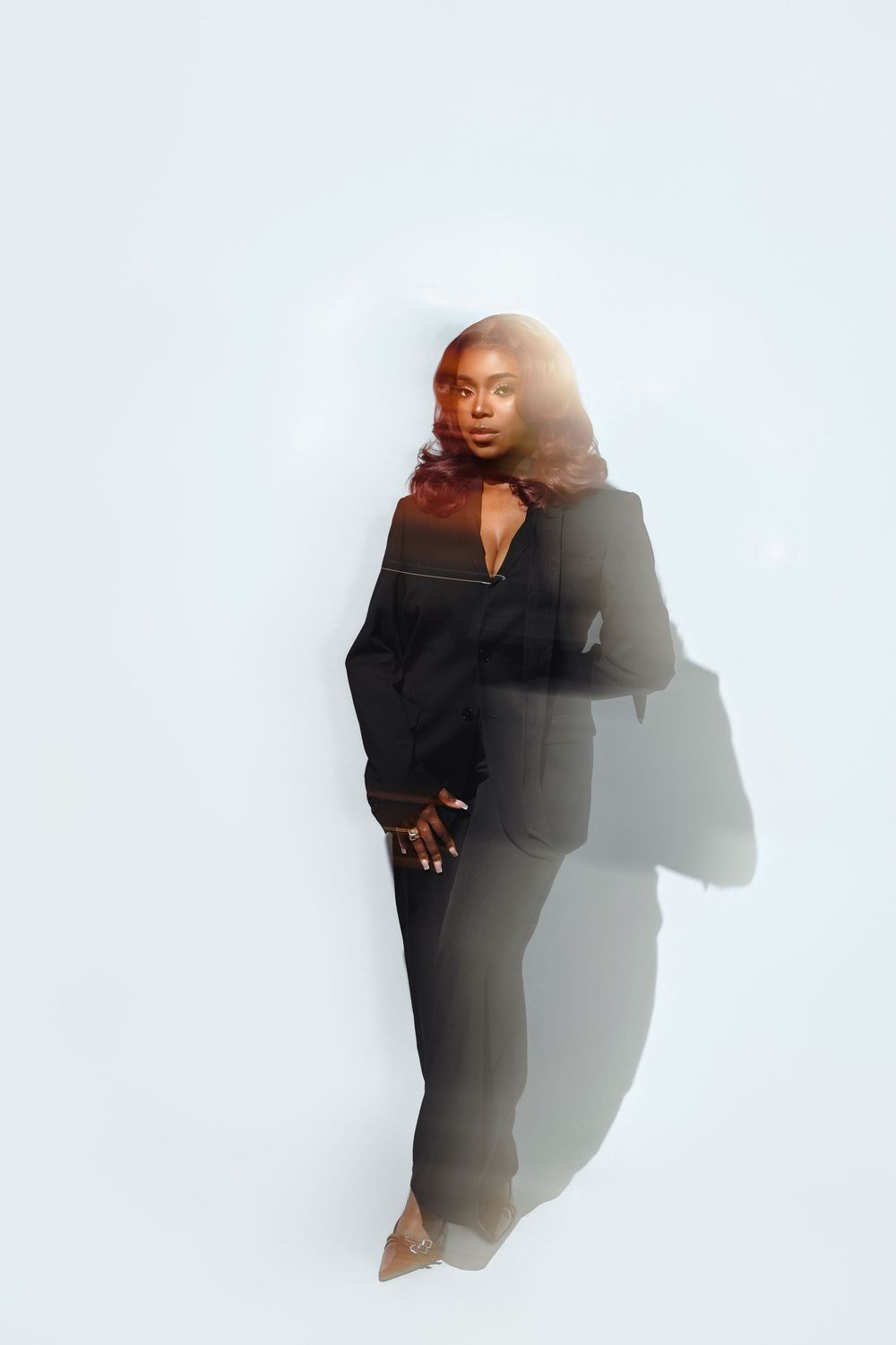 A series of artistic portraits against a white background showing a person in a black outfit creating dramatic shadows.