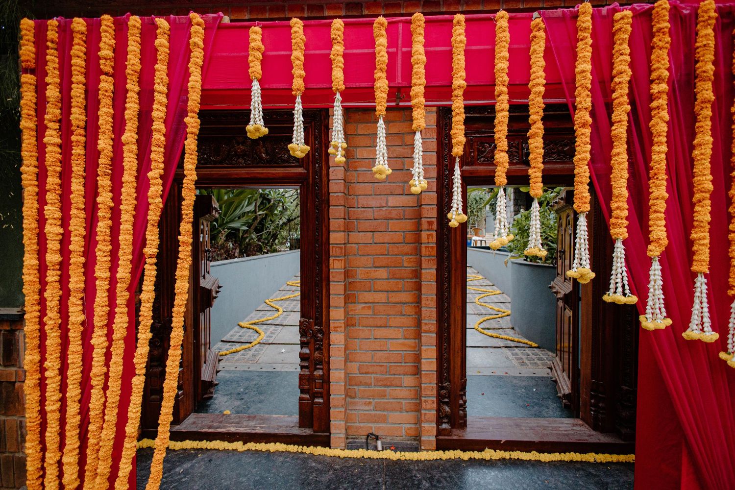 Orange and yellow marigold flower garlands hanging as traditional Indian wedding decorations.