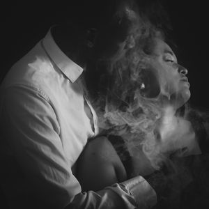 Black and white portrait of two people with smoke swirling around them in dramatic studio lighting.
