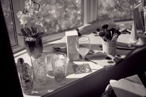 Black and white photo of elegant table settings with glassware and floral centerpieces.