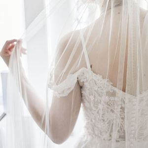 Close-up of delicate lace wedding veil and dress details in soft natural light.