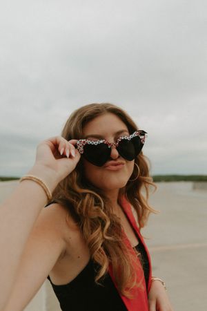 Portrait of person in sunglasses and red stole smiling at beach during sunset.