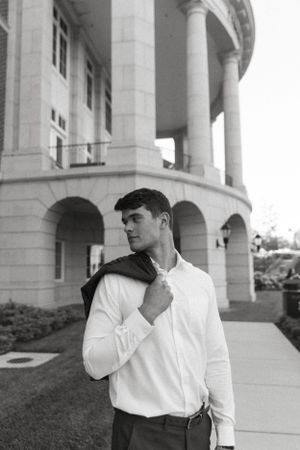 Elegant black and white portrait of a person in a white shirt against a classic columned building.