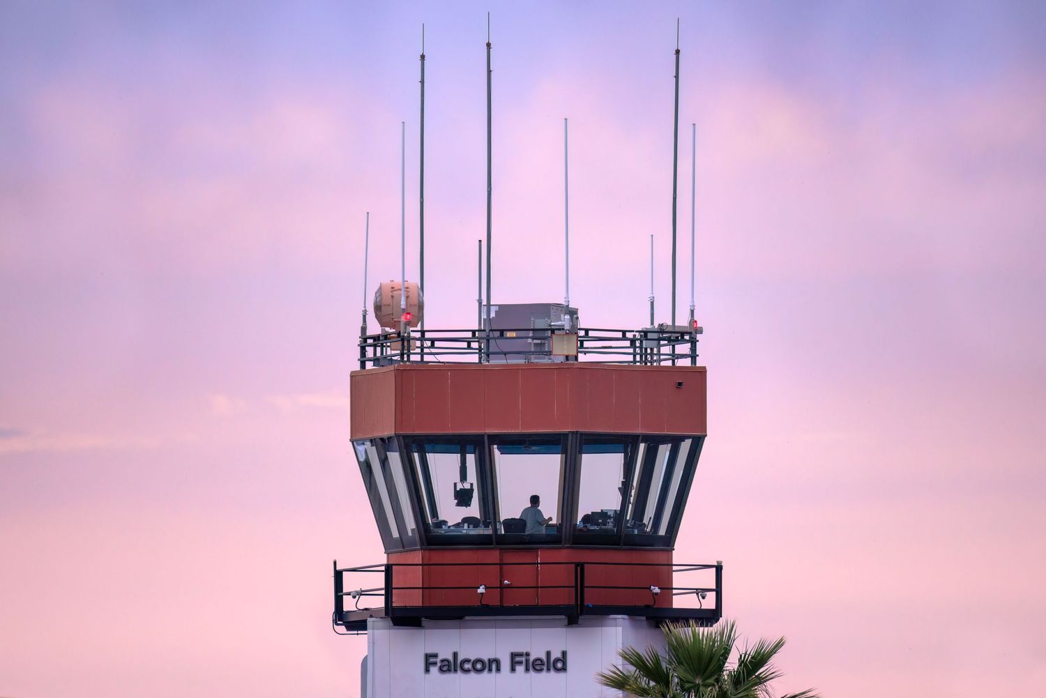 Silhouetted airport control towers at dusk with purple and pink sky creating a serene aviation backdrop.