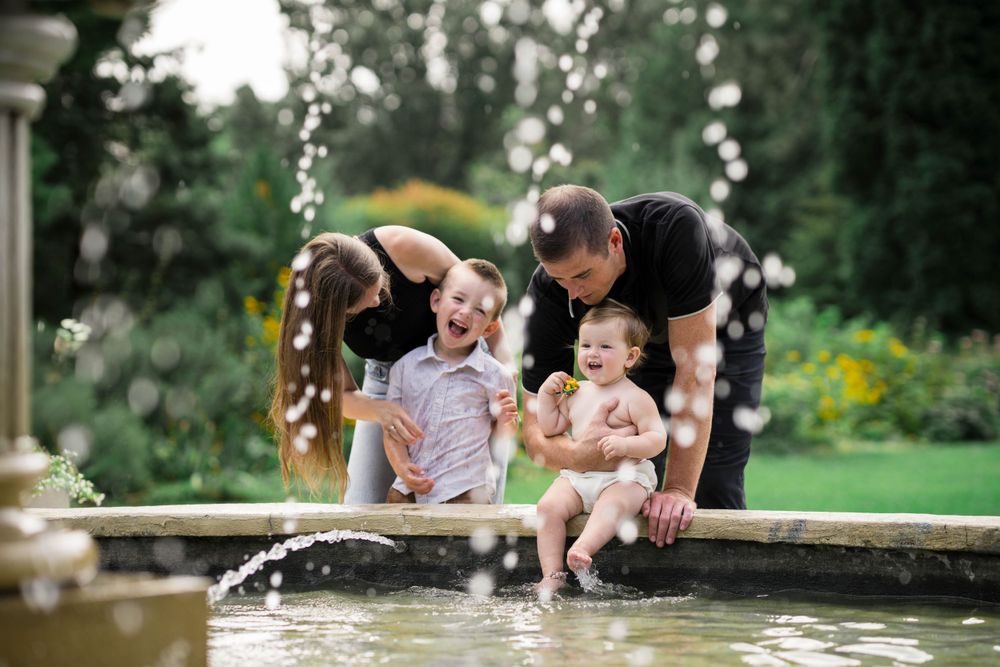 Happy family playing at garden fountain on sunny day.