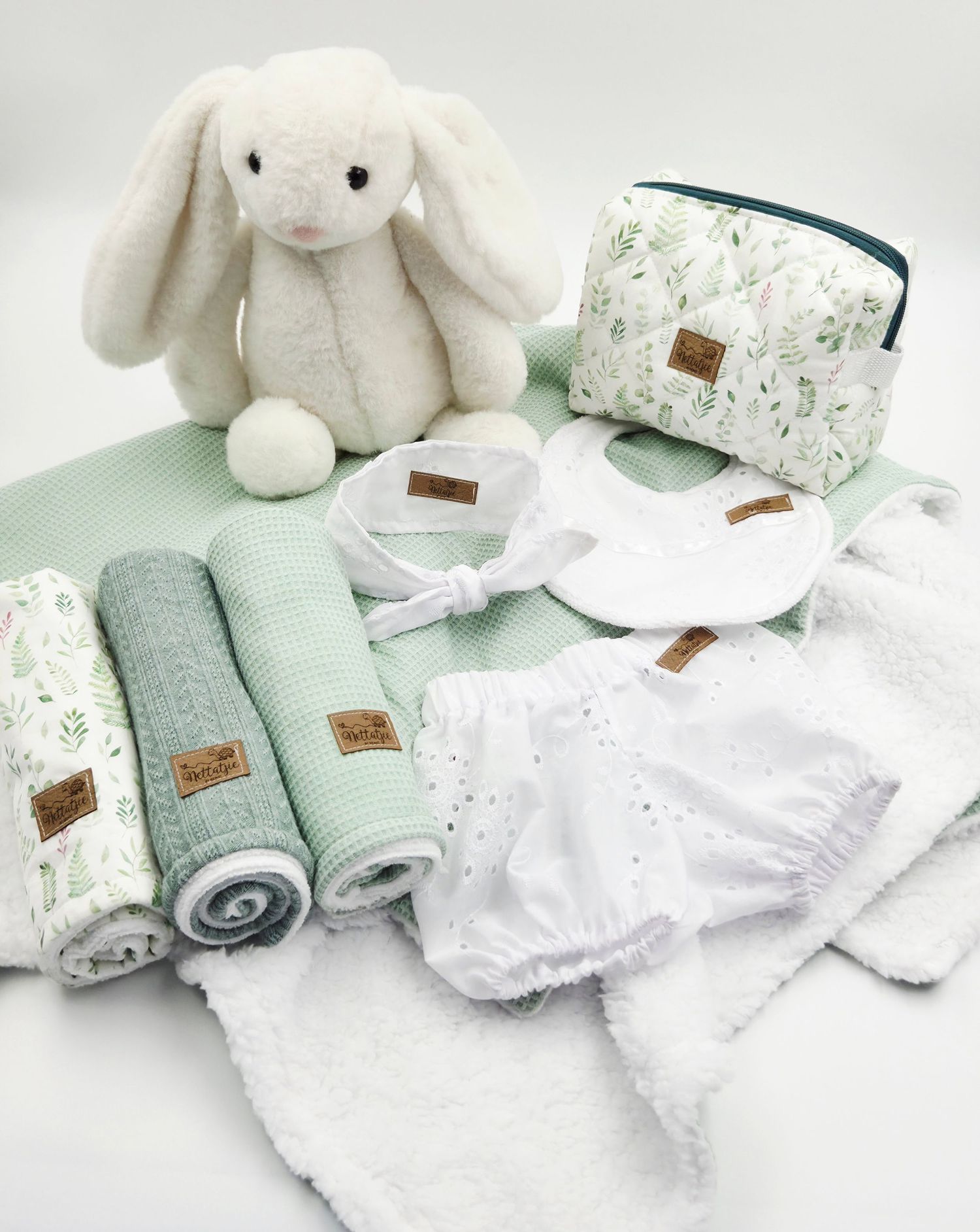 Soft white bunny plush toy displayed with mint green towels and floral print accessories.