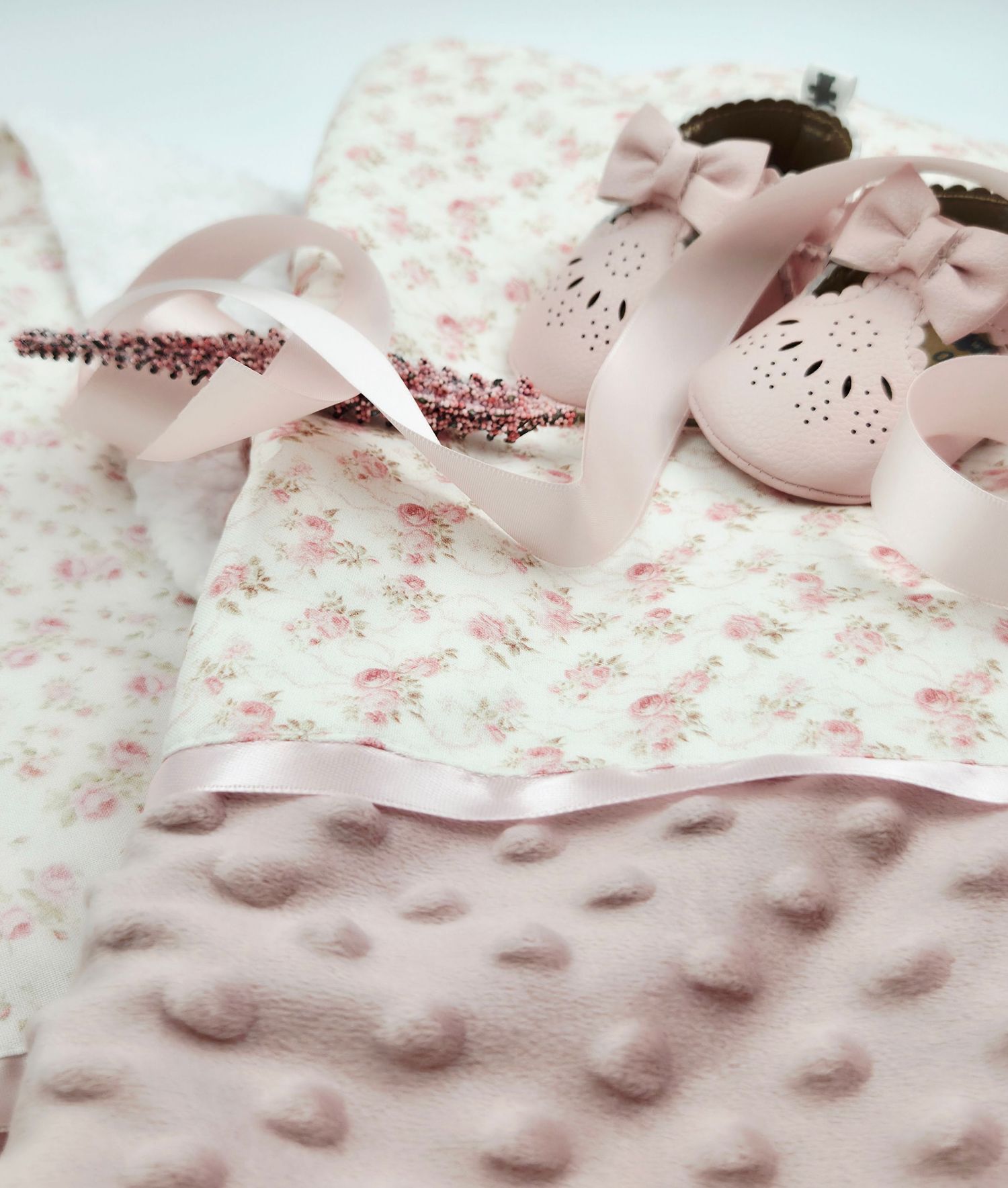 Close-up of pink minky dot fabric with floral pattern and ribbon accent.