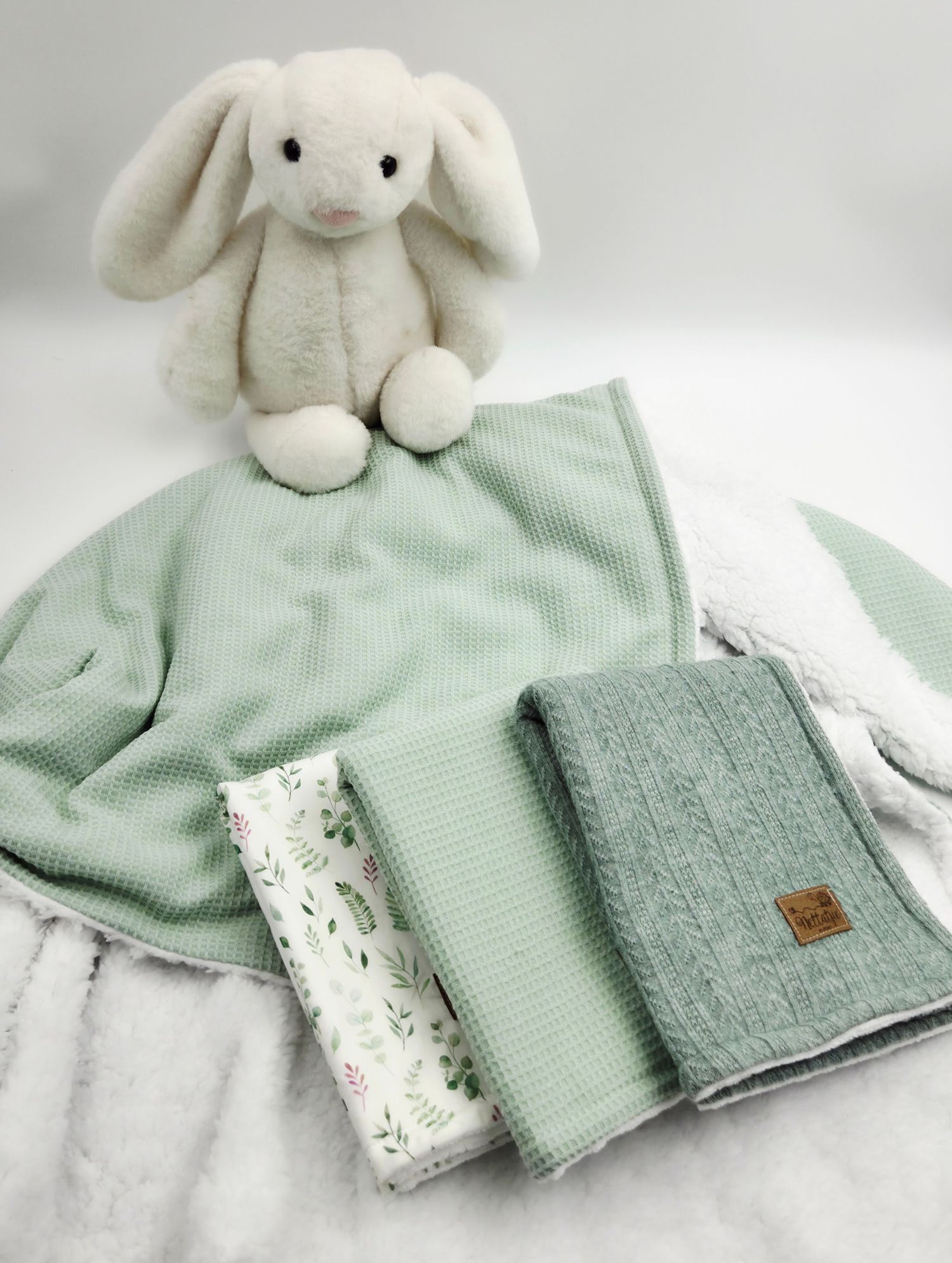 Collection of mint green and white baby blanket fabrics with plush bunny.