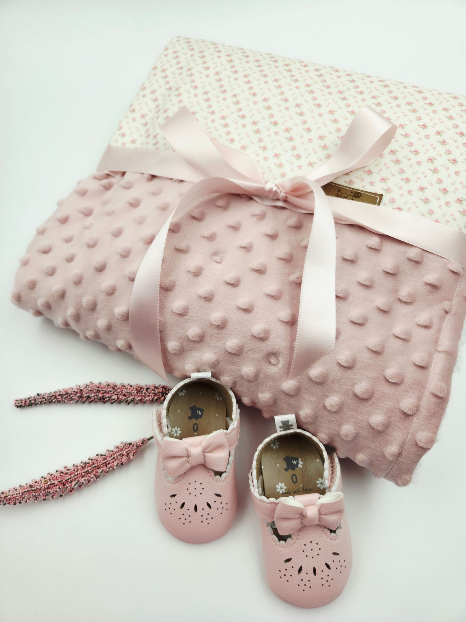 Pink dotted blanket with satin bow and matching baby shoes.