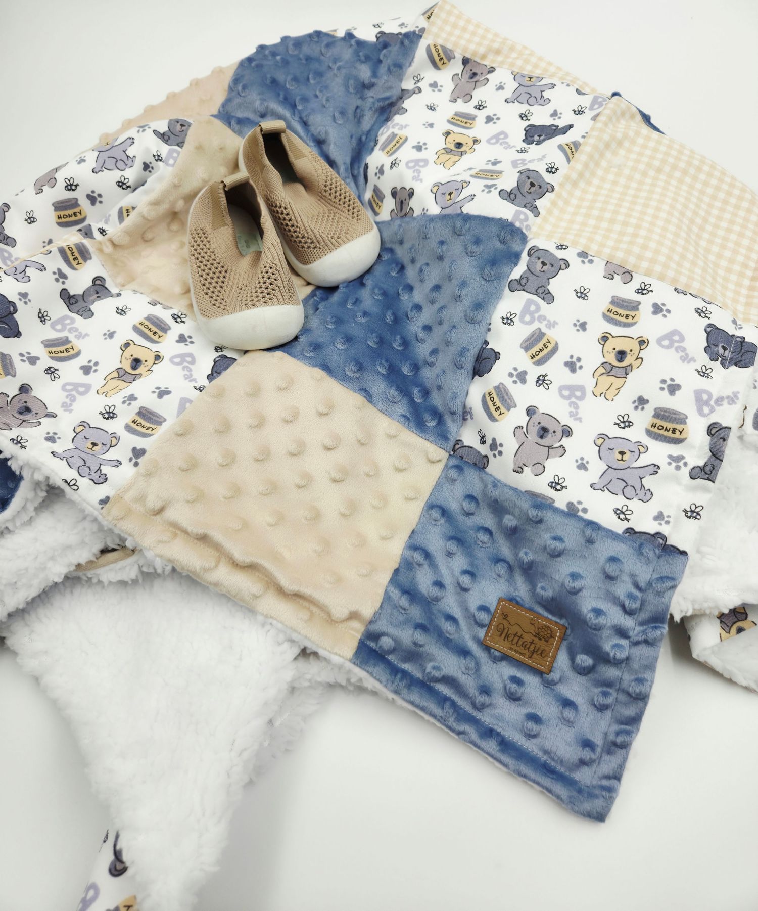Patchwork baby blanket in blue and cream with animal prints and matching beige shoes.