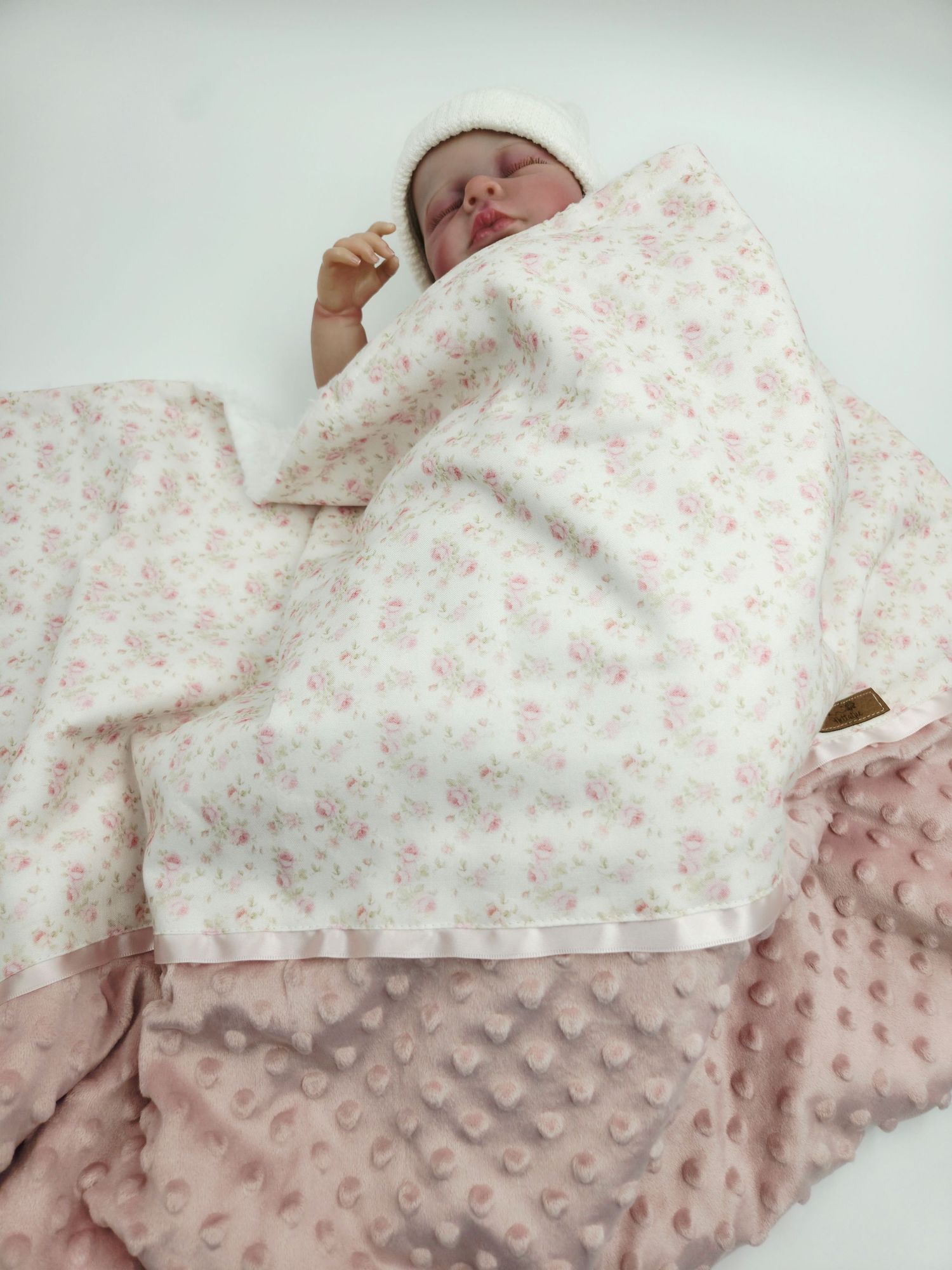 Floral print and textured pink baby blanket with delicate details.