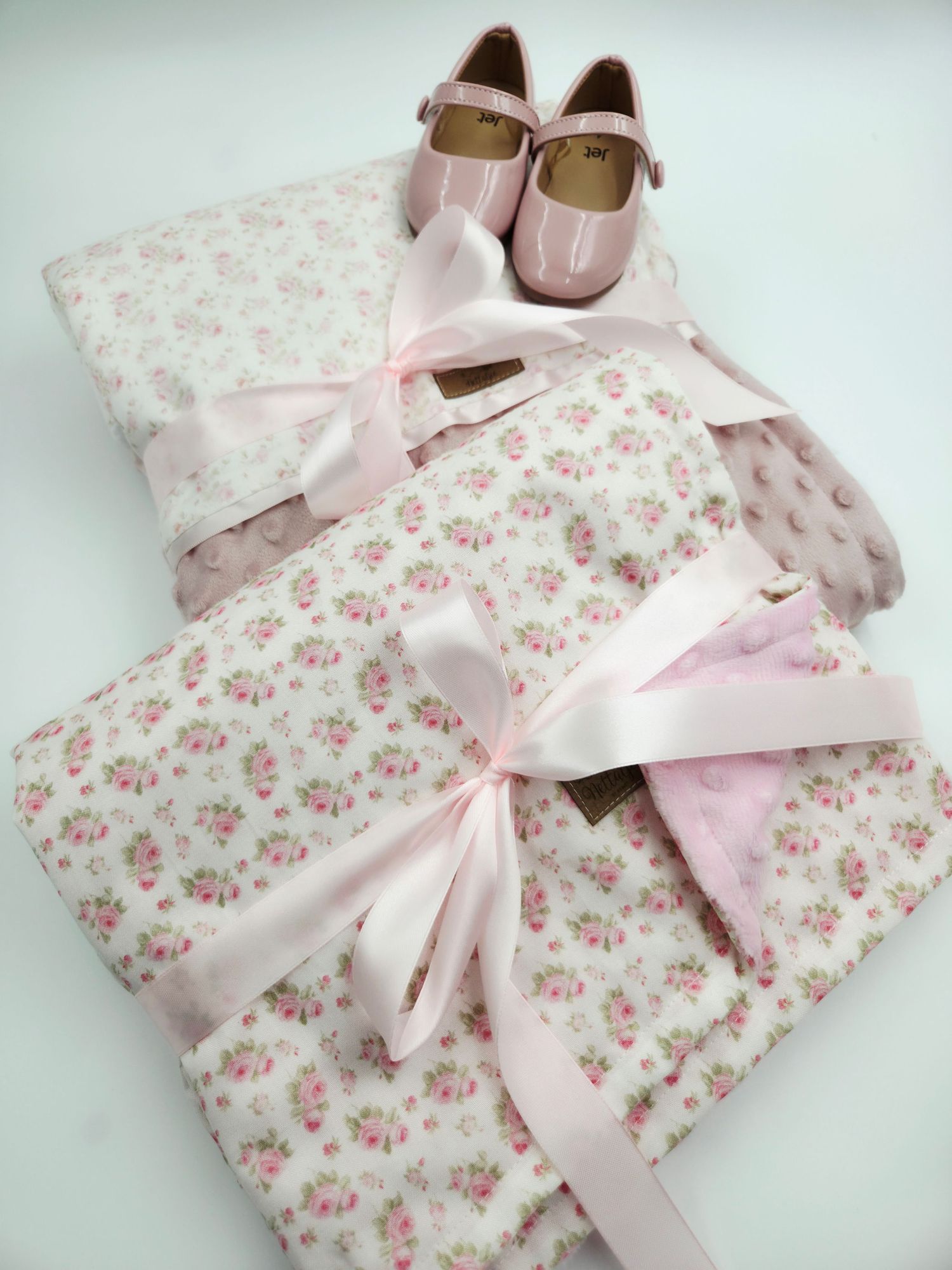 Floral print baby blanket with pink satin bow and matching shoes.