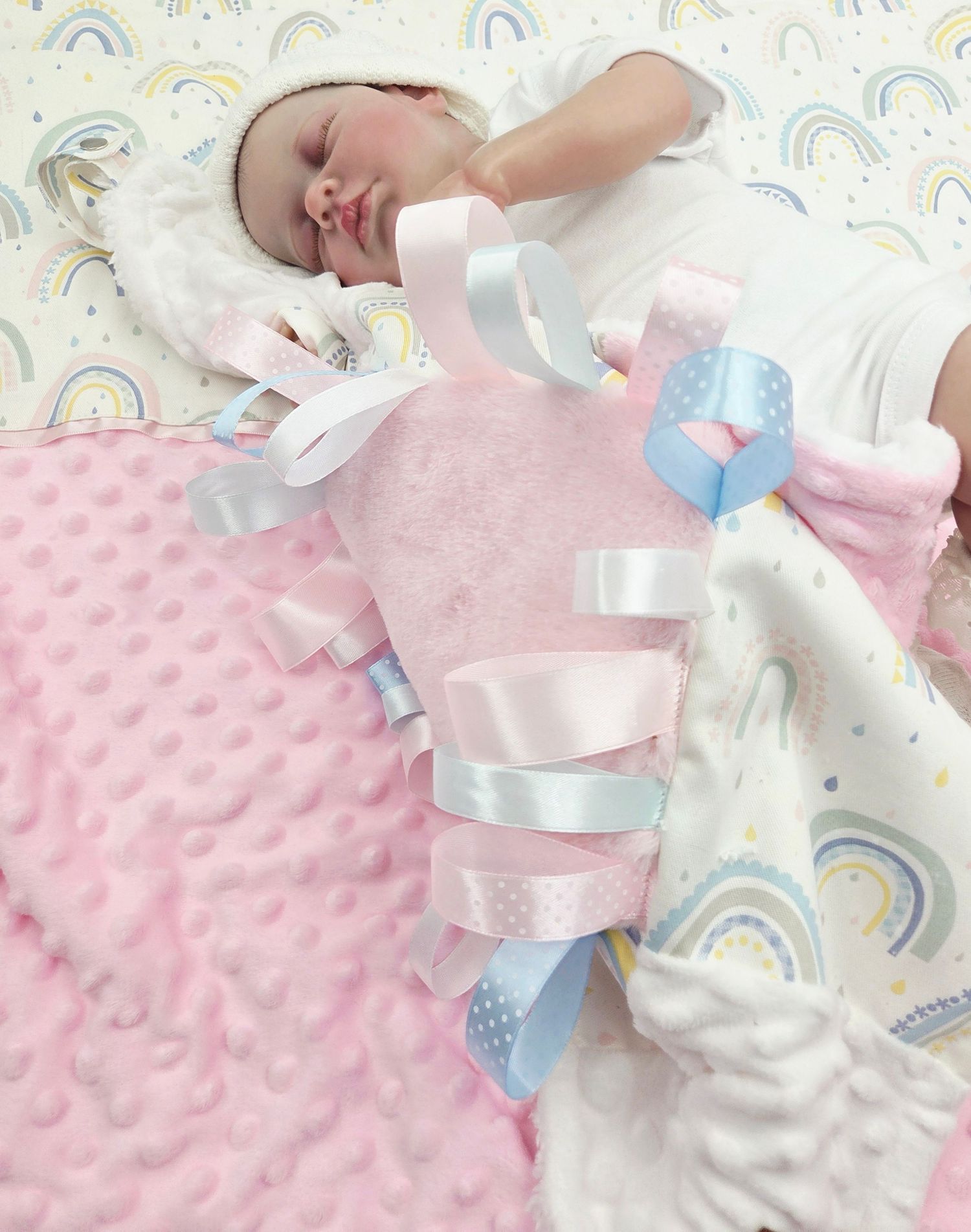 Pink and white baby accessories with rainbow pattern background and satin ribbons.