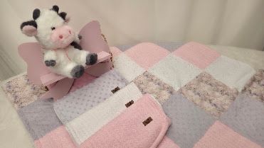 Pink and gray patchwork baby quilt with a plush cow stuffed animal toy, perfect for nursery decor.