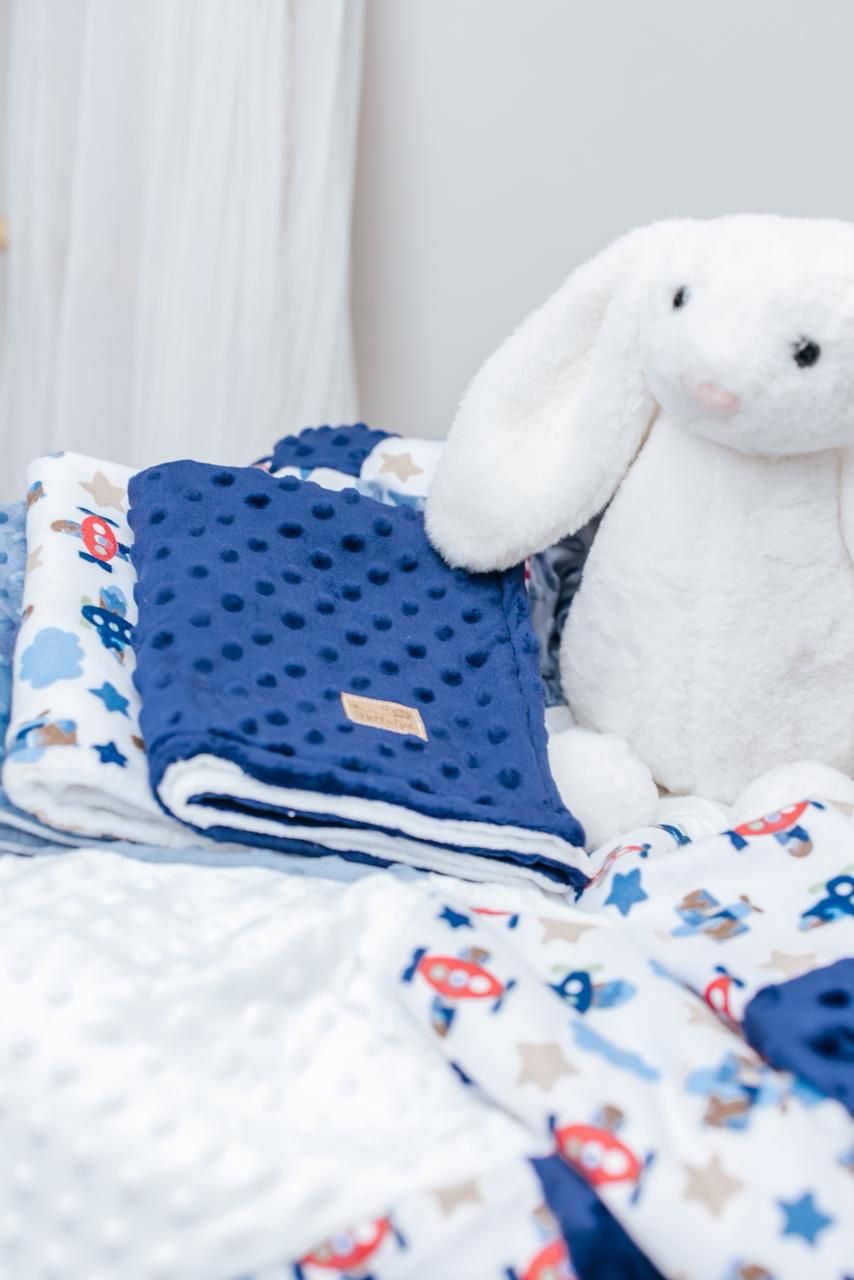White plush bunny with blue minky blanket and airplane print fabric in nursery setting.