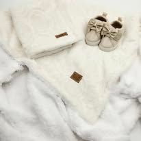 White baby clothes and shoes arranged neatly on a soft textured background.