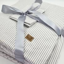 Neatly folded gray and white striped dress shirts with bow ties arranged in a row on a light surface.