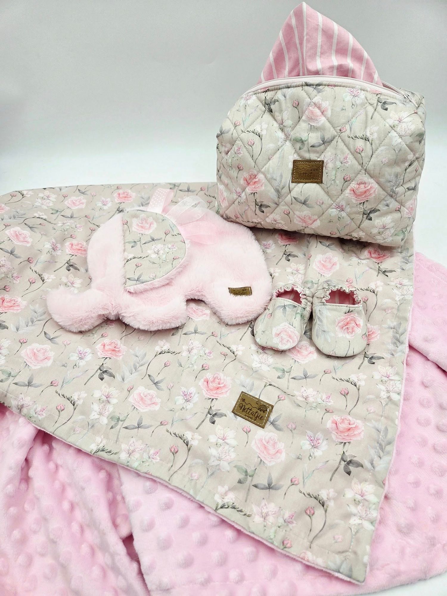 Pink and gray baby blanket with elephant print and minky dot fabric showcases matching accessories on a soft textured surface.