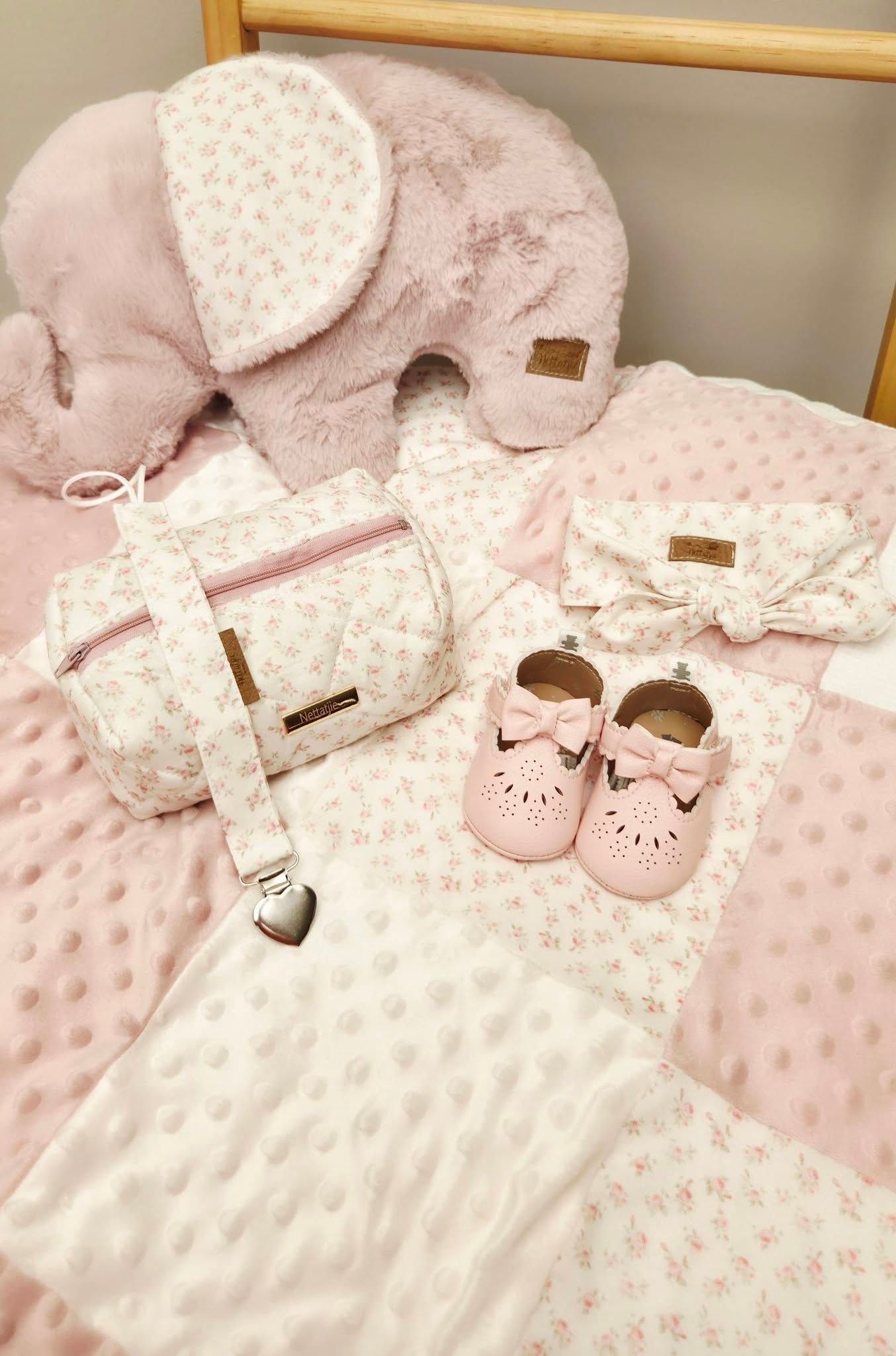 Pink baby girl gift set with floral bag, bow shoes, headband, elephant plush, and soft blanket.