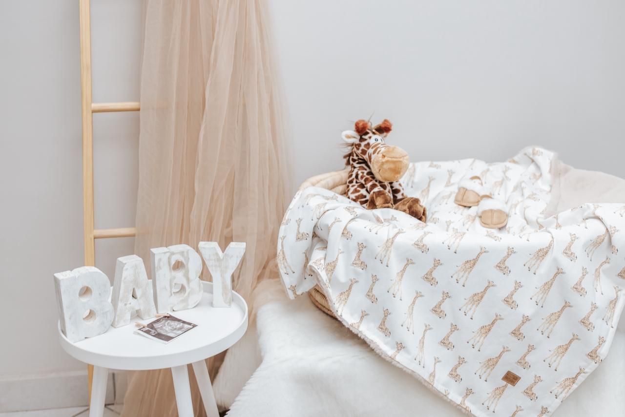 Soft beige tulle fabric draped over white furniture with plush toys and baby accessories.