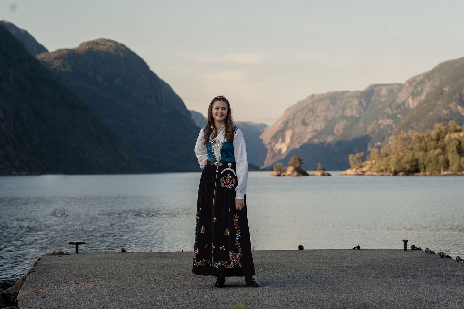 Konfirmant på bryggen med Fjell og fjord i bakgrunn