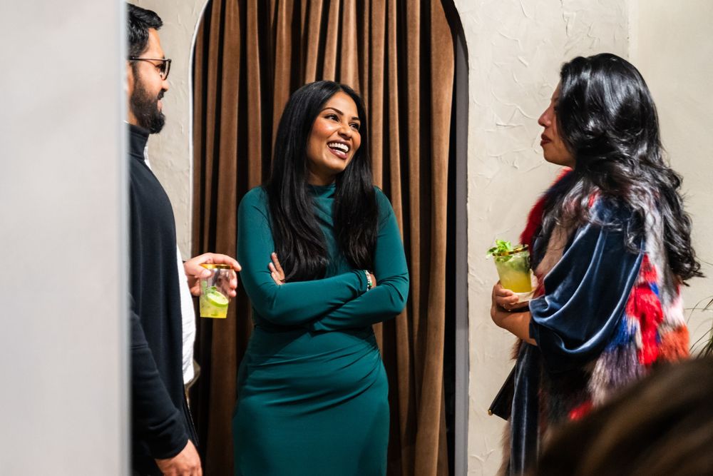 People laughing and socializing in a studio space with brown curtains.