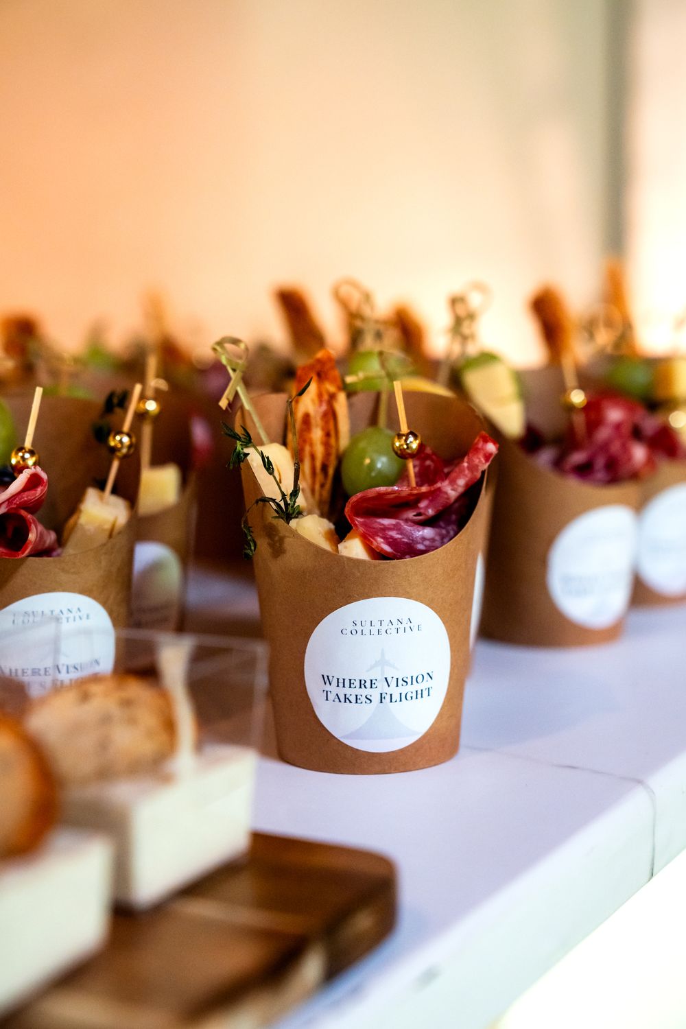 Small paper food containers with fresh salads and branded stickers arranged on white surface.