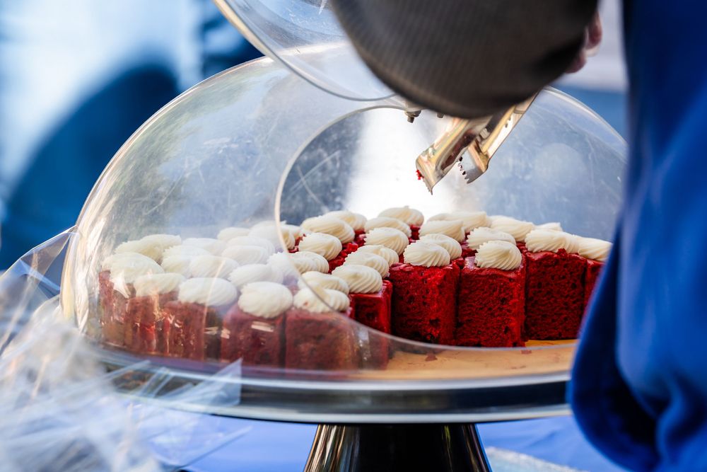 Close-up of desserts under a glass dome with red velvet treats.