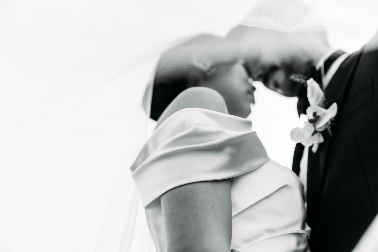 Artistic black and white silhouette of couple in formal wear sharing tender moment.