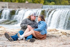Couple relaxing by a scenic waterfall during an outdoor photo session.