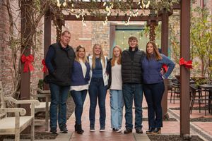 Large group portrait of people standing under a covered walkway.