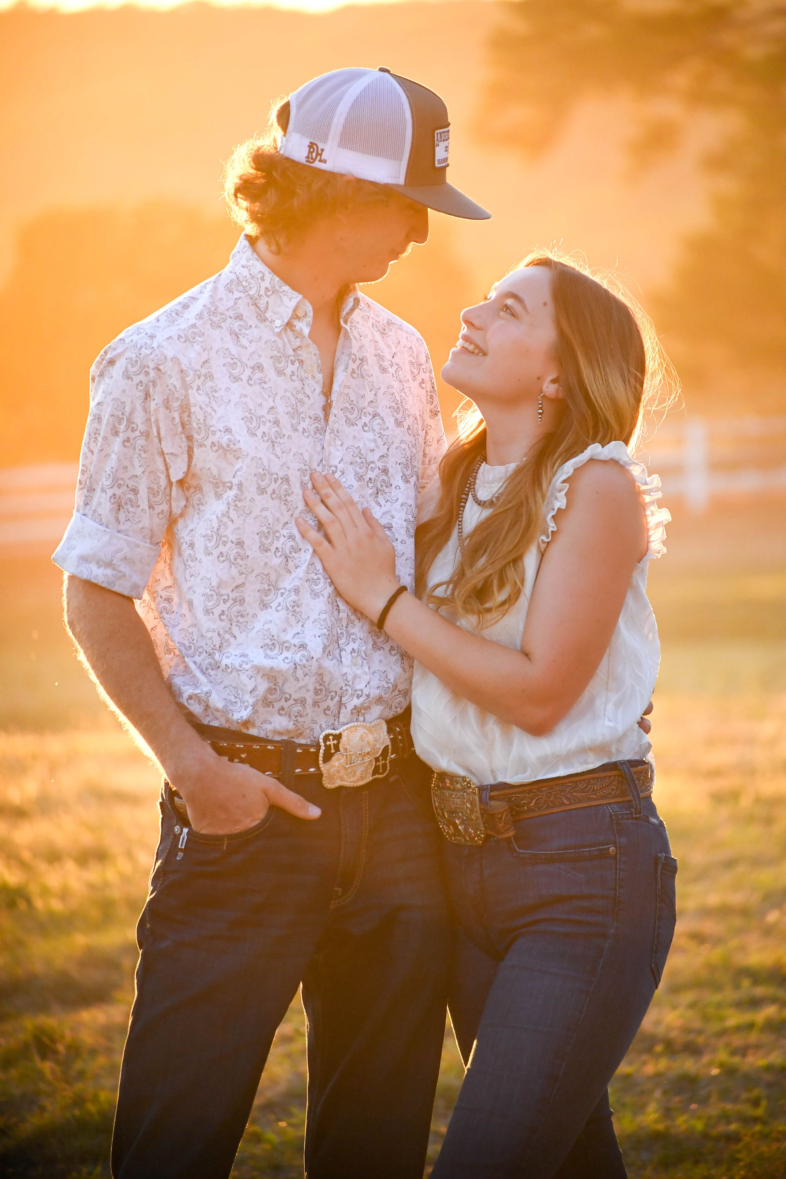 A couple shares intimate moments during a golden hour photoshoot in a field.