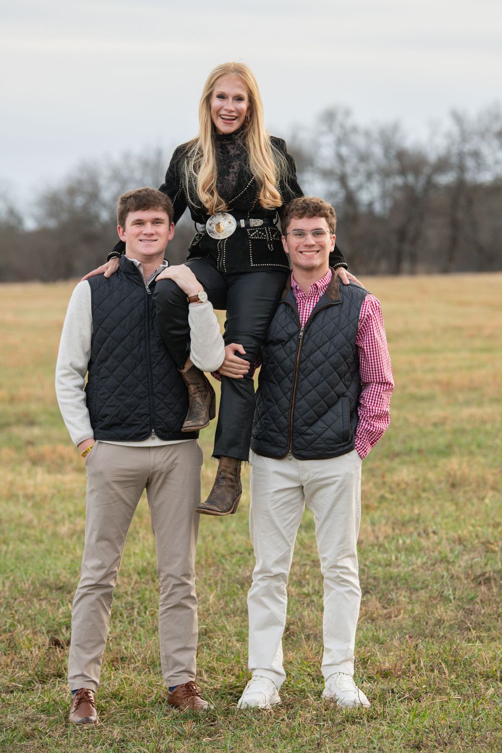 Family members wearing matching vests pose together in an open field.