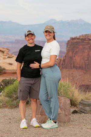 People enjoying scenic views at a desert overlook with red rock formations in the background.